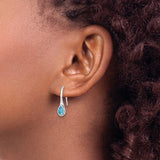 Close-up of a person with curly brown hair wearing Presco/Quality Gold Crystal Wire W/ Blue Stone Earrings, featuring teardrop-shaped blue stones that dangle just below the earlobe for an elegant touch.
