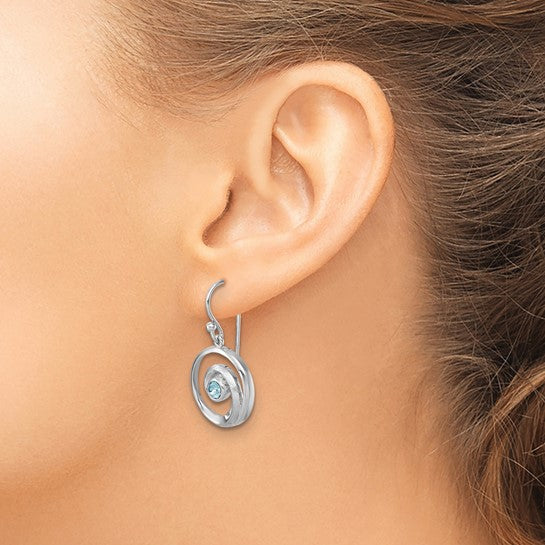 A close-up of a womans ear showcases Presco/Quality Golds Crystal Wave Dangle/Aqua Earrings, featuring sterling silver spirals and aqua Swarovski crystals that stand out beautifully against her light skin and brown hair.