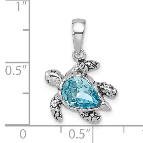 The Presco/Quality Gold Crystal Medium Aqua Turtle Pendant features a sterling silver turtle with an aqua crystal shell. Shown next to a ruler for scale, the pendant measures approximately 0.75 long by 0.5 wide.