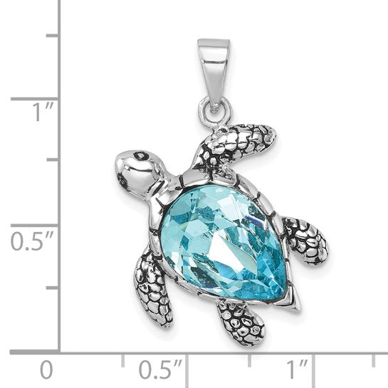 The Presco/Quality Gold Crystal Medium Turtle Pendant is a 1.25-inch sterling silver sea turtle design with a large faceted blue gemstone shell—an elegant, detailed piece of jewelry shown for scale against an inch ruler.