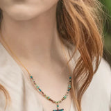 A person with long, wavy hair wears a Turquoise Beaded Dragonfly Dreams Necklace by Holly Yashi. The hypoallergenic piece complements the light blouse, set against a softly blurred background.