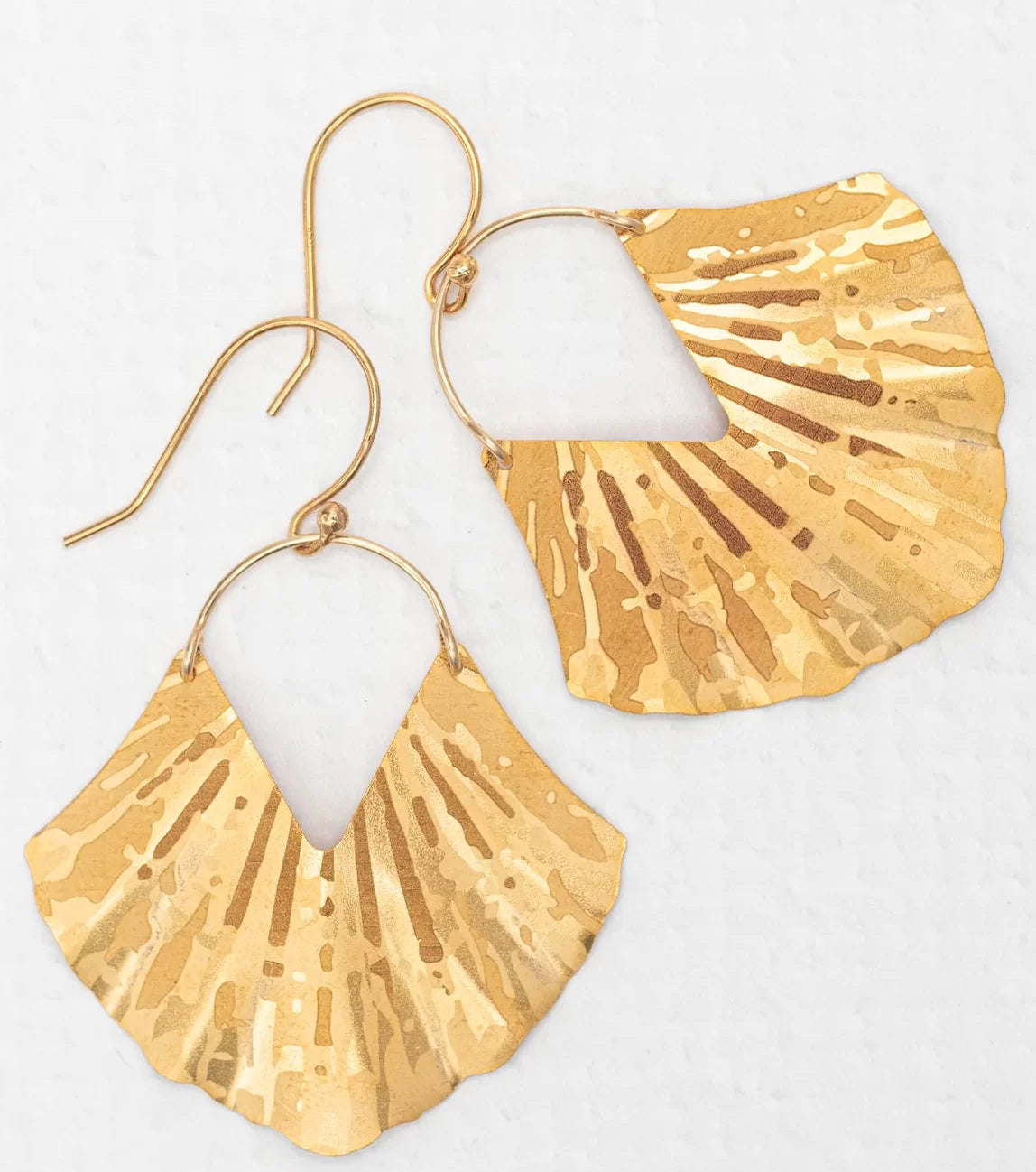 Introducing the Gold Ariel Earrings from Holly Yashi, featuring exquisite gold-plated, fan-shaped pendants with flat triangular designs. The matte finish and subtle reflections enhance their elegant and unique allure.