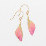 The Special Edition Flutterby Pink Earrings by Holly Yashi feature gold hooks and pink, butterfly wing-shaped charms with gold accents—ideal gold earrings to support cancer awareness. Shown on a white background.