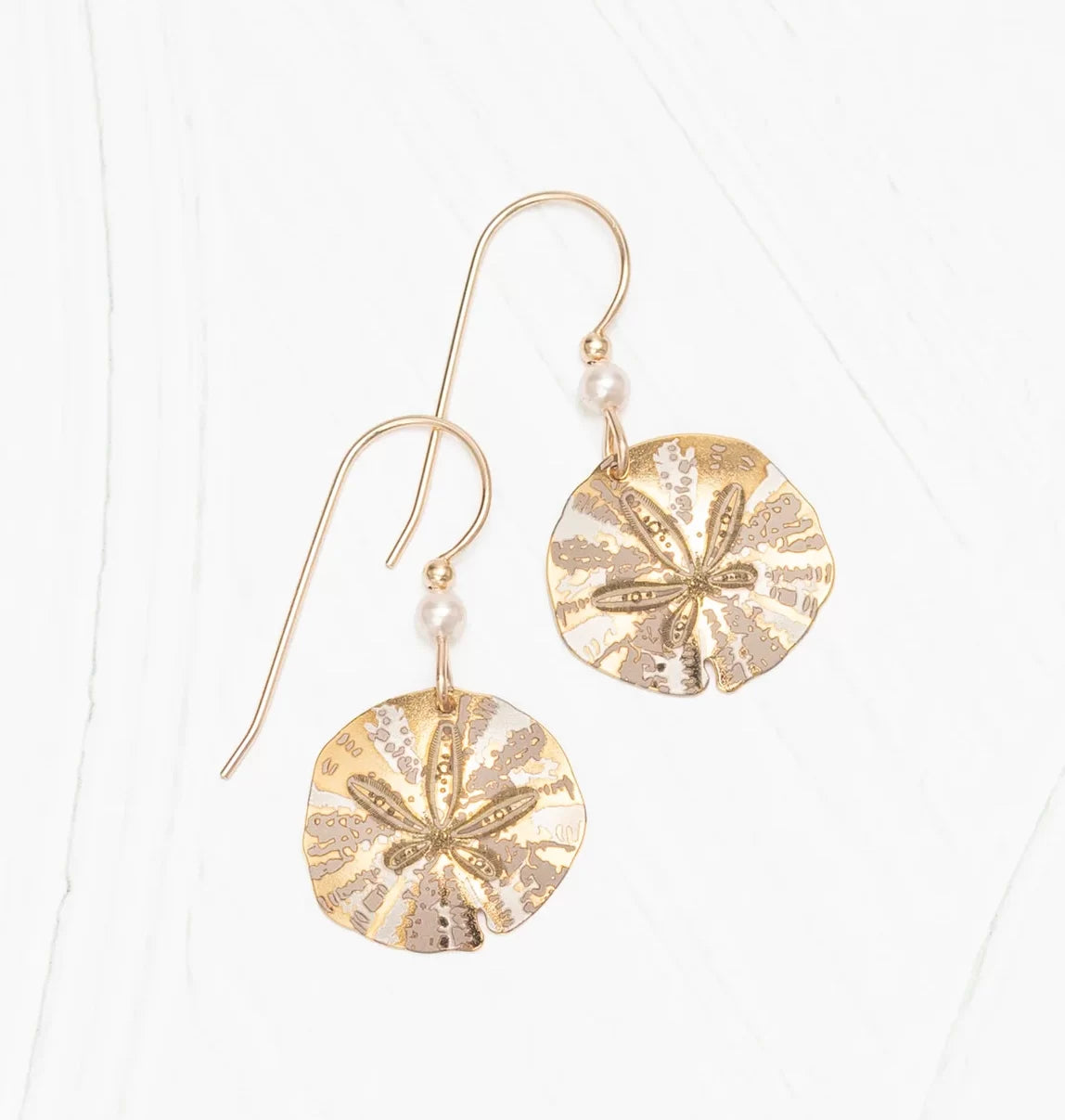 Holly Yashis Gold Sandra Shore Sand Dollar Earrings are 18k gold-filled with small pearl accents. Resting elegantly on a white surface, these hypo-allergenic earrings feature a classic hook for style and comfort.