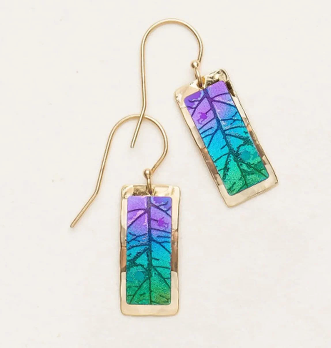 The Teal Purple Eden Drop Earrings by Holly Yashi feature two rectangular niobium earrings with delicate gold hooks, showcasing a hyper-detailed leaf design in purple, blue, and green within a thin gold frame. They are elegantly displayed on a light background.