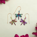 The Turquoise Dragonfly Dreams Earrings by Holly Yashi feature three iridescent dragonfly designs crafted from colorful niobium. Displayed against a light background with vibrant pink flowers, these hypo-allergenic earrings are perfect for sensitive skin and ideal for any jewelry enthusiast.