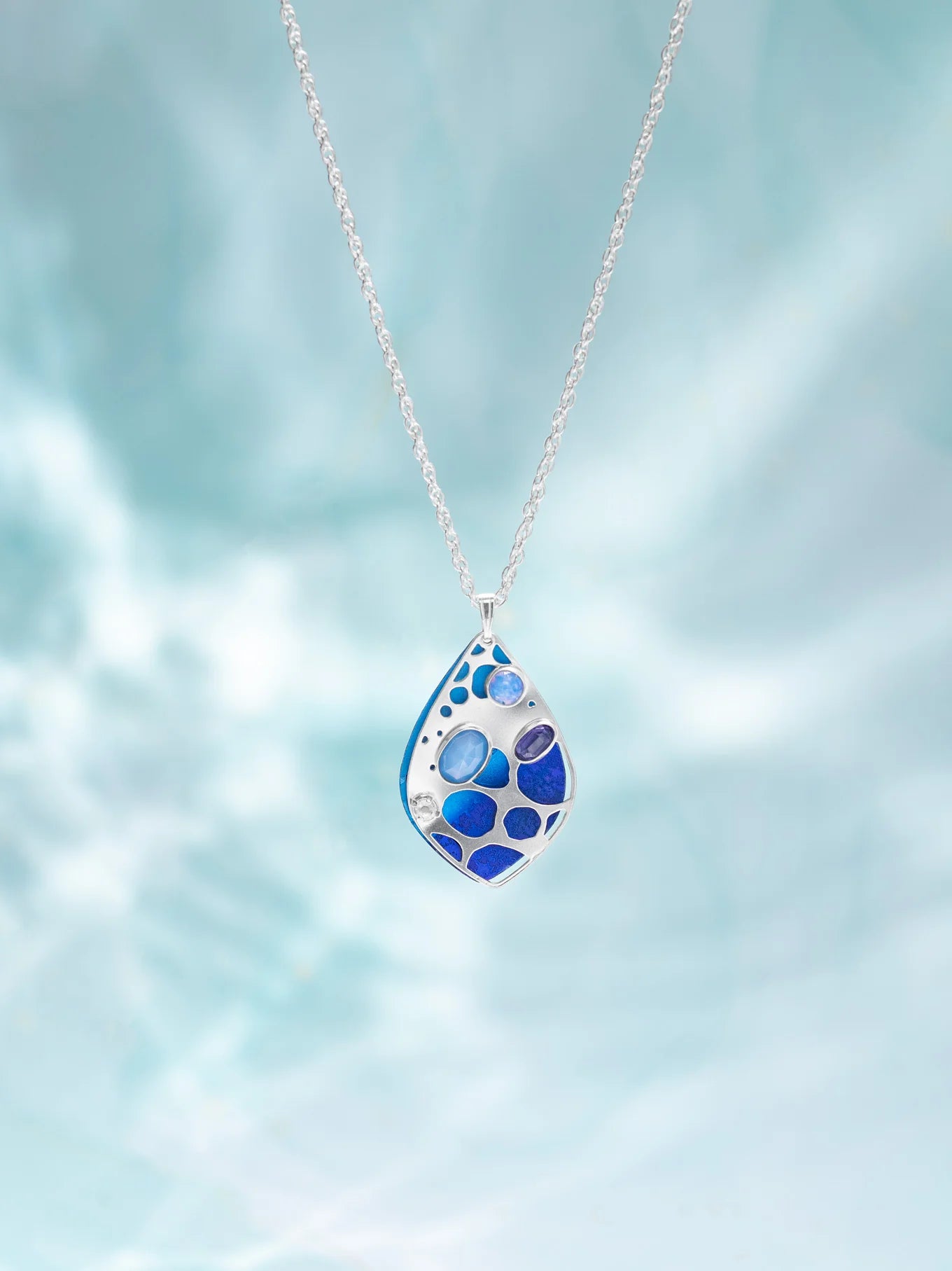 The Seashore Dreams Blue Depths Necklace by Holly Yashi is a silver masterpiece with an aqua-blue teardrop pendant adorned in various blue Austrian crystals, evoking serene ocean waves.