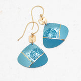 The Rowan Sky Blue Earrings by Holly Yashi feature gold hooks, geometric blue pendants, and hypoallergenic materials. Their abstract light blue, teal, and gold accents are highlighted with delicate white floral designs.