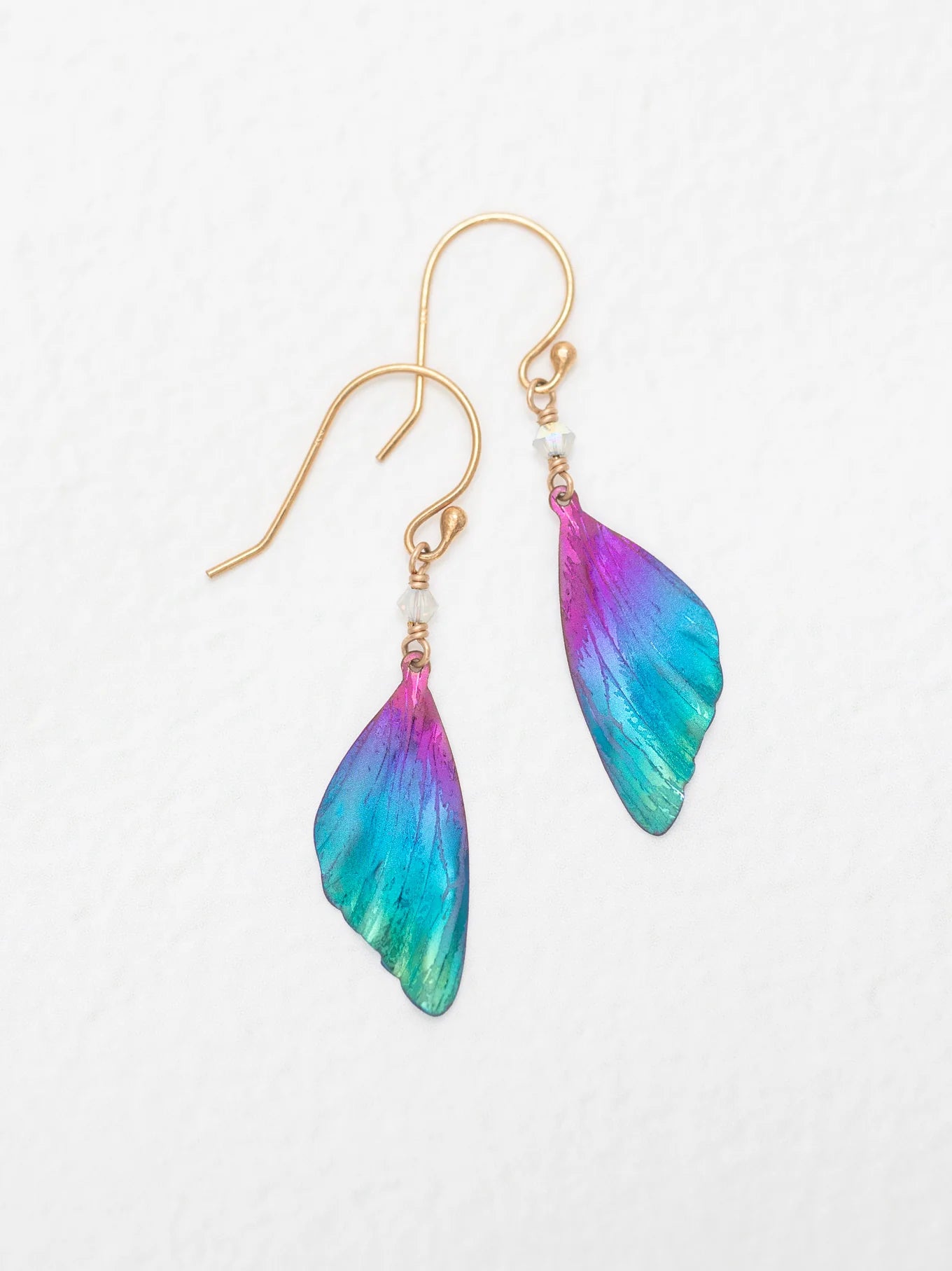 The Holly Yashi Blue Violet Flutterby Monarch Earrings feature a stunning gradient of blue, purple, and pink on wing-shaped designs attached to 18k gold-filled French wires, embodying elegance and vibrant charm.