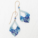 The Marisol Forever Blue Earrings by Holly Yashi feature gold hooks, hypoallergenic niobium wires, blue beads, and layered teardrop pendants with a blue floral pattern on light blue, shown on a white textured surface.