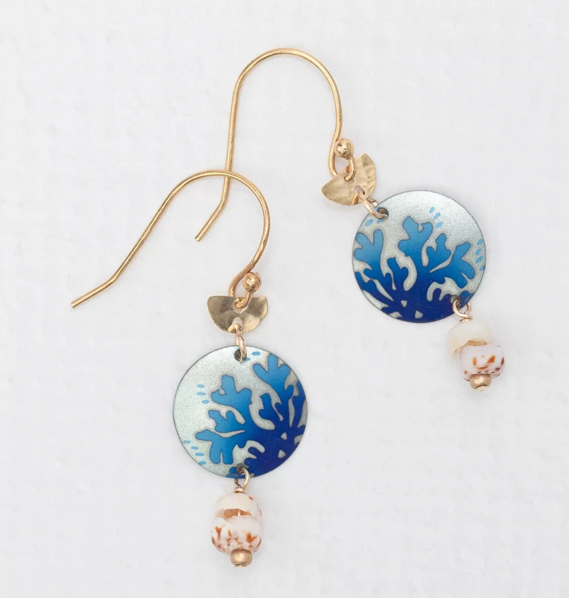 Meet the Coral Reef Seashore Blue Earrings by Holly Yashi: Gold hook earrings featuring blue coral-patterned charms, a beige and brown speckled bead on white, crafted with hypo-allergenic materials for sensitive ears.