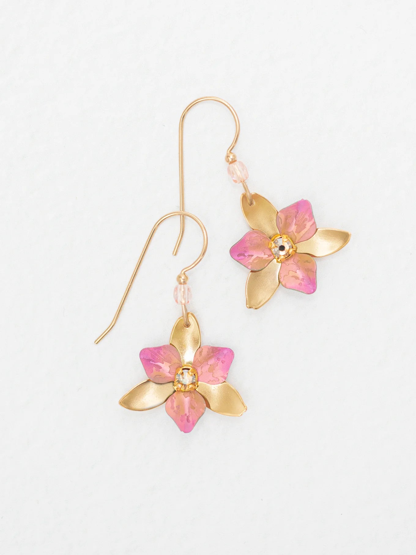 The Special Edition Orla Drops Earrings by Holly Yashi feature gold flower-shaped hooks with pink accents and sparkling Austrian crystals at the center, shown on a plain white background.