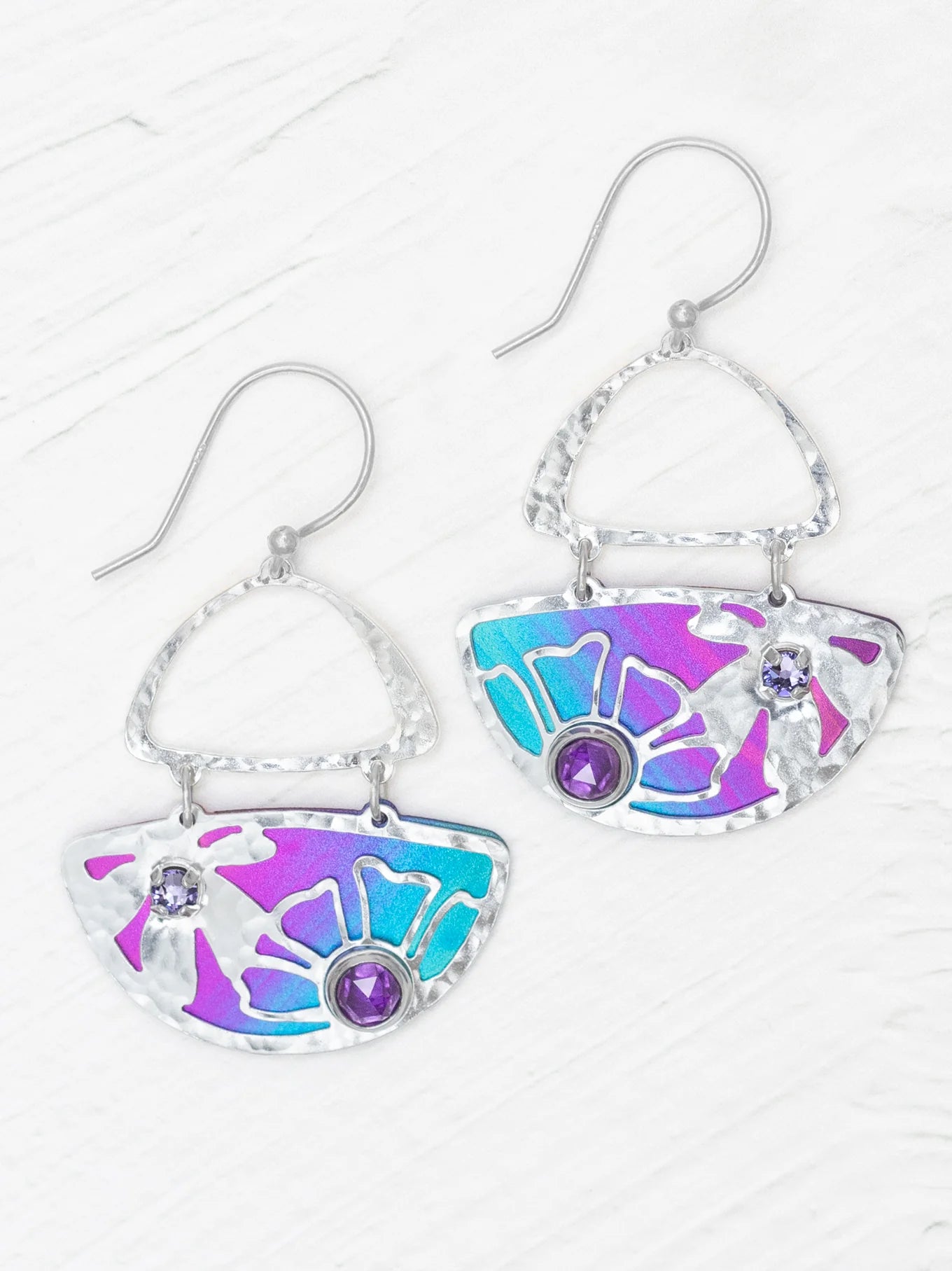 The Demi Calypso Earrings by Holly Yashi are hammered silver drop earrings with blue and purple enamel fan shapes, each adorned with two round purple gemstones and finished with sterling silver posts.