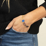 A person in a black sweater and blue jeans rests their hand in a pocket, showcasing the Holly Yashi Alex Multi Color Bracelet with vibrant, gem-inspired stones on their wrist.