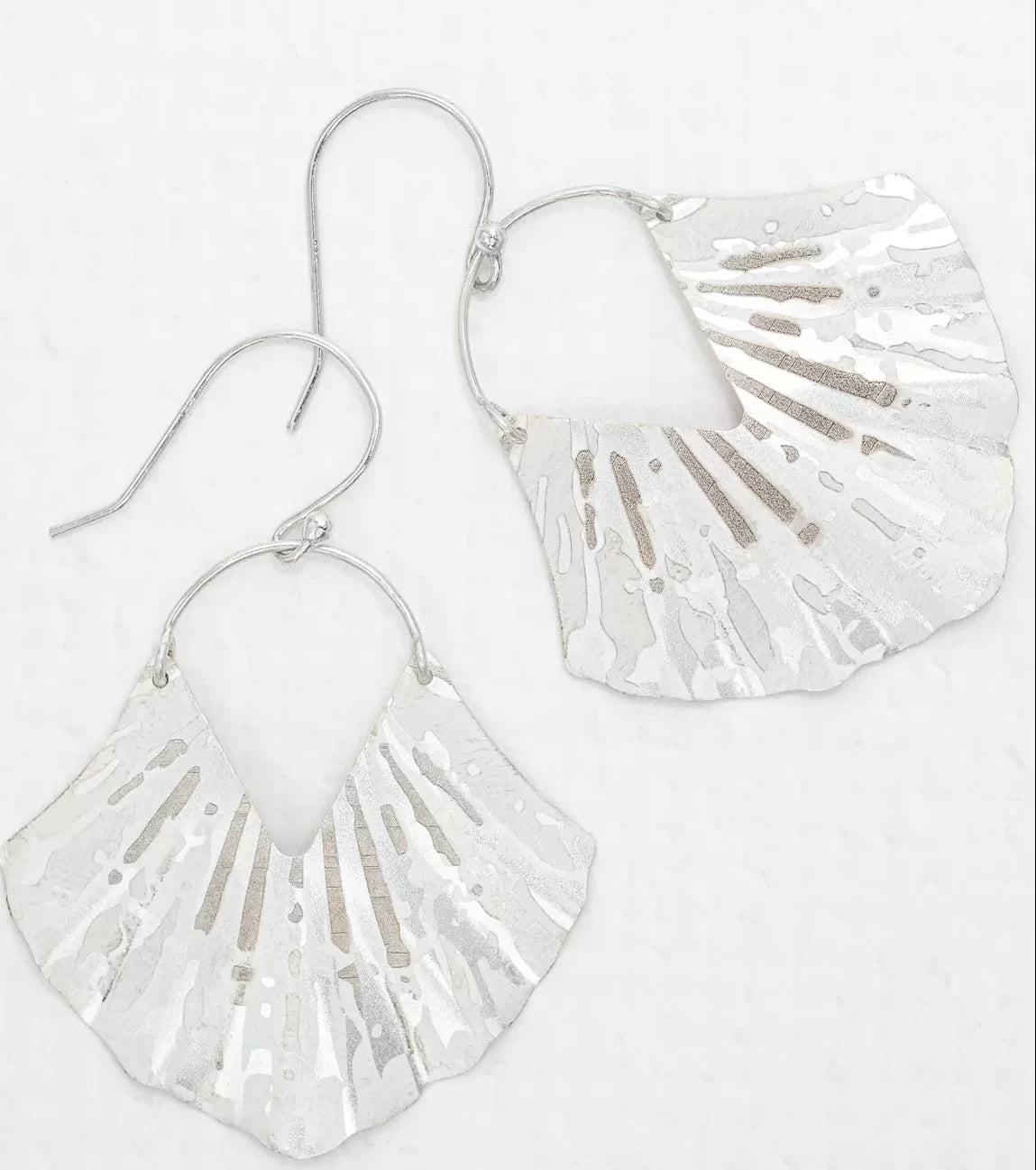 The Silver Ariel Earrings by Holly Yashi feature textured silver with scalloped edges and an abstract hammered ocean-inspired design. Hypo-allergenic and dangle-style, they include hook attachments and are showcased against a white background.