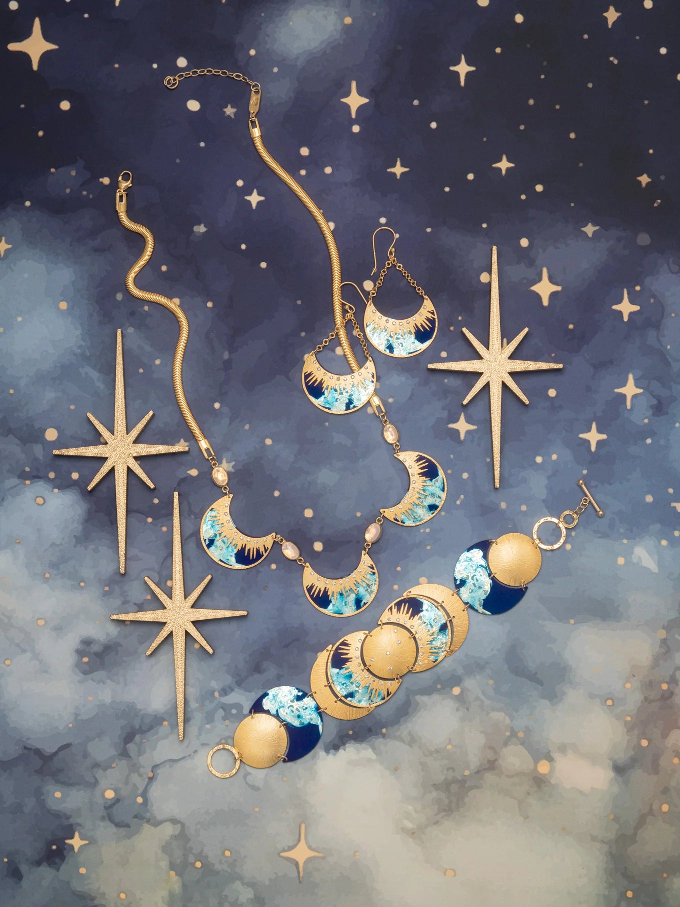 Jewelry displayed on a starry midnight blue background features the Holly Yashi Selena Midnight Blue Bracelet and matching earrings with blue, white, and gold crescent moons, accented by four gold star-shaped ornaments.