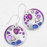 Introducing the Ocean Depth Sea Plum Earrings by Holly Yashi: round silver earrings with abstract cutouts, purple and blue accents, featuring two gemstones—an oval magenta and a round light pink—on textured discs. These hypo-allergenic beauties sparkle with shimmering Austrian crystals.