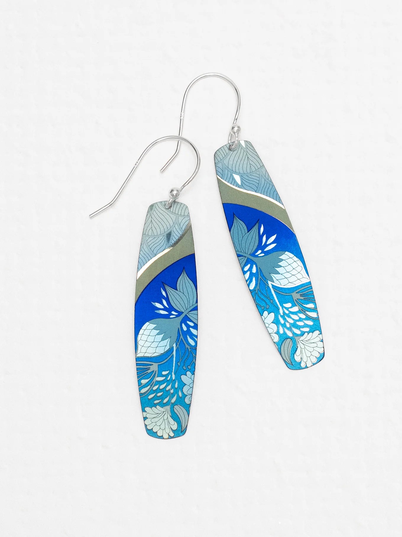 The Malia Kai Blue Earrings by Holly Yashi are long, rectangular handcrafted niobium earrings with silver hooks, featuring blue with white and light blue floral designs and a metallic accent. Hypoallergenic—ideal for sensitive ears.