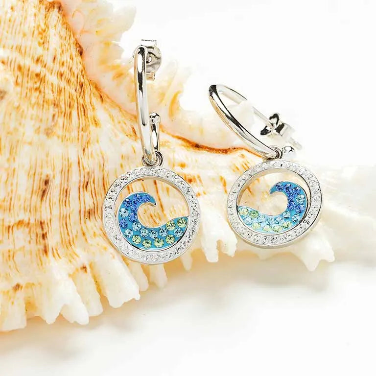 Shanores Ocean Jewelry collection features Swarovski Crystals Sapphire/Aqua Post Hoop Wave Earrings, showcasing circular earrings with blue and teal patterns against a textured seashell design in sterling silver.