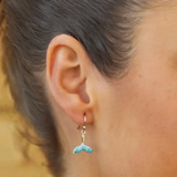 Close-up of a persons ear wearing Shanores Swarovski Crystals Aqua Mermaid Tail Earrings- Ocean Jewelry. The shimmering blue accents and intricate design are enhanced by sparkling crystals, with a softly blurred background emphasizing the elegant details.