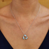 The individual showcases Shanores Swarovski Crystals Three Dolphins Necklace- Ocean Jewelry, worn with a deep V-neck top against a simple, warm-colored background.