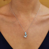 A woman dazzles in a Shanore Swarovski Crystals Dolphin and Baby Pearl Necklace, her V-neck top enhancing the ocean-inspired elegance against a warm, neutral backdrop.