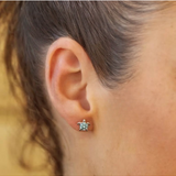 Close-up of a person wearing Shanores Swarovski Crystals Turtle Aqua Stud Earring-Ocean Jewelry. The sparkling piece stands out against the skin, with its turquoise hue, while the softly blurred background adds an air of mystery.