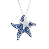The Shanore Swarovski Crystals Dark Blue Starfish Necklace-Ocean Jewelry features two sterling silver pendants: a larger starfish with blue Swarovski crystals and a smaller one with clear crystals, both on a delicate chain embodying an oceanic theme.