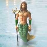 The Atlantis Ornament by December Diamonds features a merman with long hair and beard, wearing a green scaled tail and golden ornaments. Holding a trident in the ocean, his hand-painted details make him ideal for holiday decor.