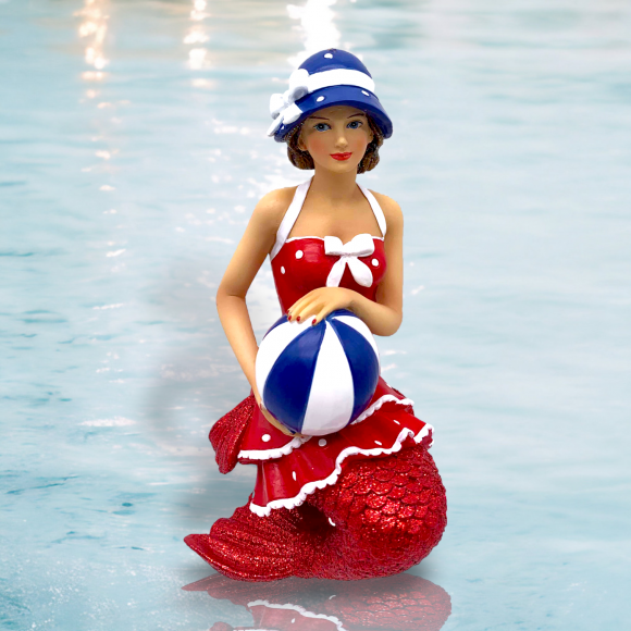 The hand-painted Bathing Beauty Ornament from December Diamonds boasts a red vintage-style swimsuit with white accents, a blue and white striped hat, and a coordinating beach ball, encapsulating holiday decor essence against a water-like backdrop.