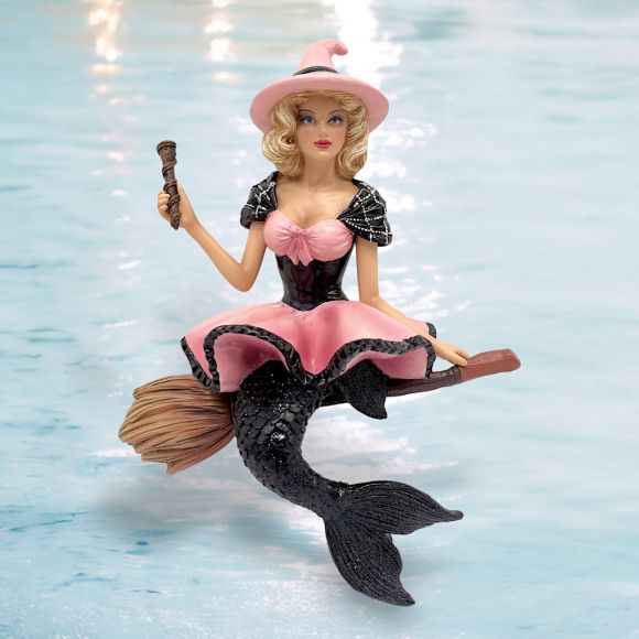 The Baywitched Ornament by December Diamonds is a whimsical holiday decor piece featuring a pink-dressed witch with a black mermaid tail and broomstick, set against a water-themed backdrop. An exquisite blend of whimsical charm, its reminiscent of mystical mermaid ornaments.