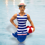 Mr. Beach Balls Ornament by December Diamonds is a whimsical male doll with a blue glittery tail, striped swimsuit, and straw hat posed on one knee holding a red and white beach ball, making it a captivating merman decoration for your holiday décor.