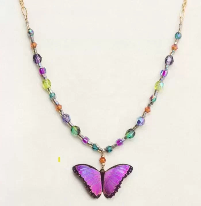 Introducing the Ultra Violet Bella Butterfly Beaded Necklace by Holly Yashi, featuring a striking purple butterfly pendant and a vibrant chain of multicolored beads in shades of purple, green, and orange—perfect for adding a splash of color to any plain background.