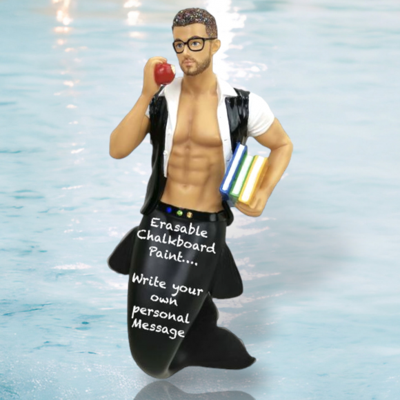 The December Diamonds Hot 4 Teacher Ornament features a merman with glasses, holding an apple and books, wearing an open shirt, and sporting a chalkboard tail inscribed “Erasable Chalkboard Paint... Write your own personal Message.”.