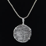 The Treasure Shoppe Inc.s Large Potosi Frame Coin pendant from Atocha Shipwreck Coins displays a large, round coin in a sterling silver bezel with intricate, worn details, reminiscent of the classic designs, suspended against a black background.