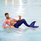 The December Diamonds Miami Ornament features a mermaid-themed merman doll with a blue tail, beard, and colorful floral shirt. It lounges on water holding a tropical drink, creating a relaxed beach or poolside vibe perfect for holiday decor.