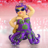 The Miss Fran 3 Ornament by December Diamonds is a quirky holiday decor piece, showcasing a figure in a glittery purple octopus costume with green spots, sunglasses, a beaded necklace, and a floral headpiece. Its hand-painted and set against a blurred pink and white background.