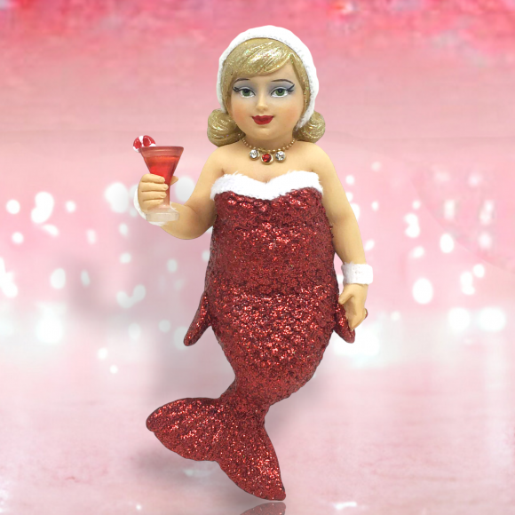 The Miss Jolly Ornament by December Diamonds showcases a mermaid with a red glittery tail and Santa hat, holding a cocktail glass. Set against a pink sparkly gradient, it captures whimsical holiday decor charm.