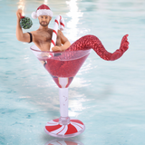 December Diamonds Mistletoe Santa Ornament features a charming merman with a red glittery tail, sipping from a martini glass filled with shimmering red glitter. He holds mistletoe in one hand and a candy cane in the other, set against an enchanting backdrop.