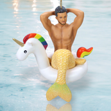The Mr. Unicorn Ornament by December Diamonds features a hand-painted merman with a glittery tail lounging in a unicorn float, complete with a rainbow mane, horn, and heart decoration. The soft blue water enhances the summery charm of this holiday decor piece.