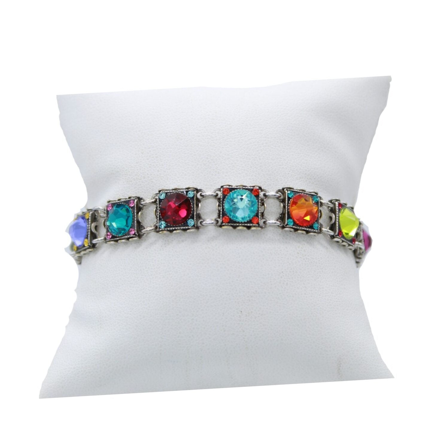 Fireflys Rainbow Square Multi Color Bracelet features vibrant square gemstones in blue, red, orange, green, and purple set in silver. Handmade in Guatemala and hypo-allergenic for all-day comfort, its showcased on a white cushioned stand.