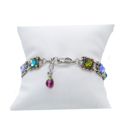 The Rainbow Square Multi Color Bracelet by Firefly is a beautiful handmade hypoallergenic piece from Guatemala, featuring multicolored square gemstones on a silver chain with a small red charm at the clasp, elegantly presented on a white cushion.