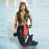 The Salvador Ornament by December Diamonds features a hand-painted merman pirate with long hair, a red headband, earrings, and a black vest holding a sword. His black glittering tail contrasts beautifully with the light blue water background—perfect for your holiday decor collection.