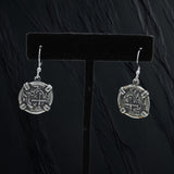 The Treasure Shoppe Inc.s Small Wrapped Coin Earrings feature Atocha coin designs crafted from sterling silver. Displayed on a black stand, they glimmer with intricate, antique-inspired details perfect for fans of unique, timeless accessories.
