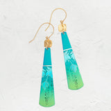 Presenting the Turquoise Tula Earrings by Holly Yashi: exquisite teardrop earrings with a teal-to-lime gradient, floral pattern, and gold hooks. Made from hypo-allergenic niobium, they elegantly hang against a textured white backdrop.