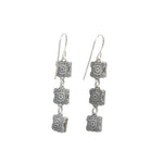 The Rainbow Square Multi-Color Earrings by Firefly feature three vertically linked silver squares engraved with intricate floral patterns, hanging elegantly from simple hooks. These fair-trade handmade earrings offer a unique and stylish design for art enthusiasts.
