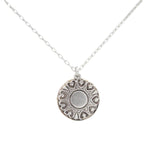 The Playa Sand Dollar Soft Necklace by Firefly features a hypo-allergenic silver round pendant with heart-shaped accents and a central circle, inspired by beach sand dollars, displayed against a white background.