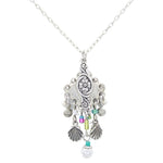The Beach Pearl Diamond Shell w/Fringe Soft Necklace by Firefly features handmade Guatemalan craftsmanship with a floral pendant, purple, green, and turquoise beads, plus silver shell and sphere charms.