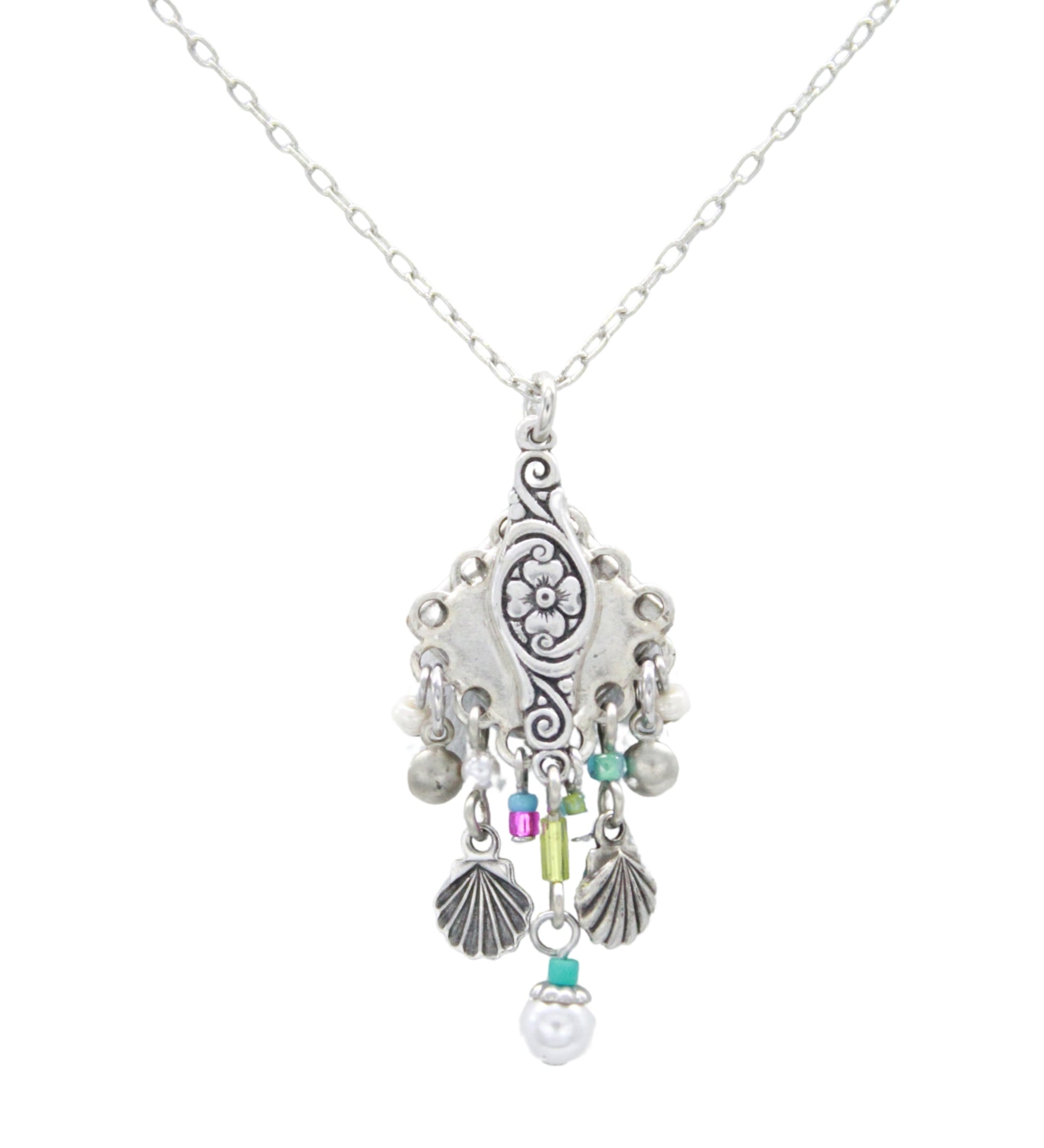 The Beach Pearl Diamond Shell w/Fringe Soft Necklace by Firefly features handmade Guatemalan craftsmanship with a floral pendant, purple, green, and turquoise beads, plus silver shell and sphere charms.