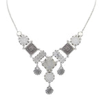 The Firefly Ocean Elaborate Soft Necklace features an ornate pendant with geometric and filigree designs, plus three shell-shaped charms—handmade in Guatemala.